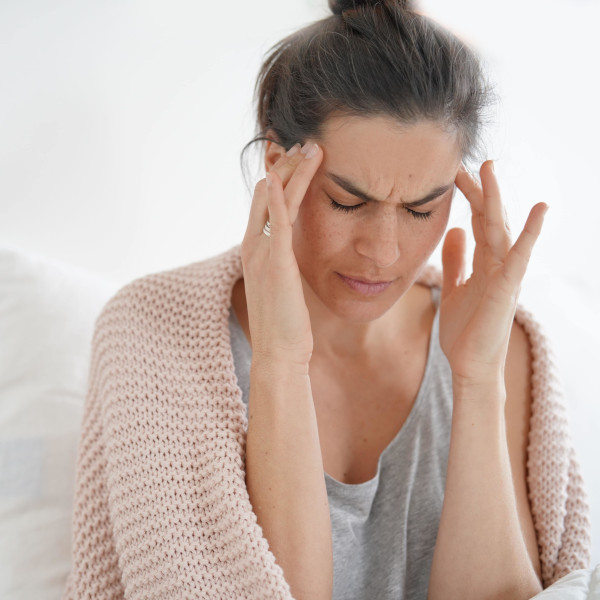 Woman sitting down and rubbing her temples with a look of frustration and discomfort