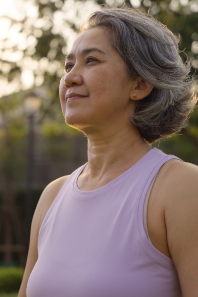 Smiling asian woman looking into the distance, empowered, soft sunlight in background