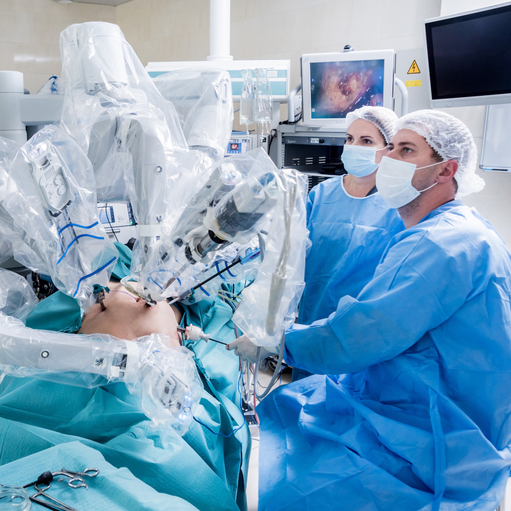 Two physicians sitting in the OR in scrubs performing robotic minimally invasive endometriosis excision surgery