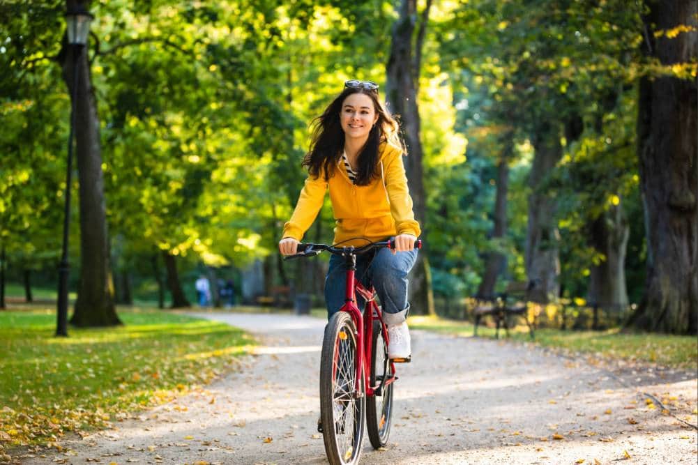 A woman smiling while enjoying a bike ride in nature, pain free after a successful endometriosis excision surgery