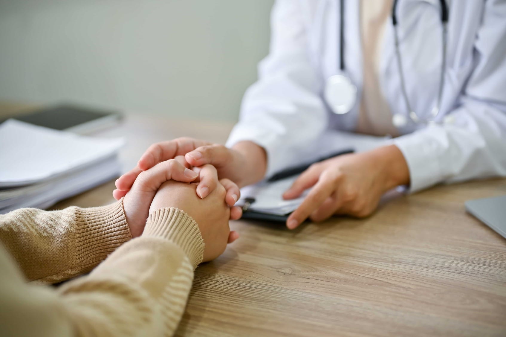 Doctor comforting a patient, resting their hand on the patient's