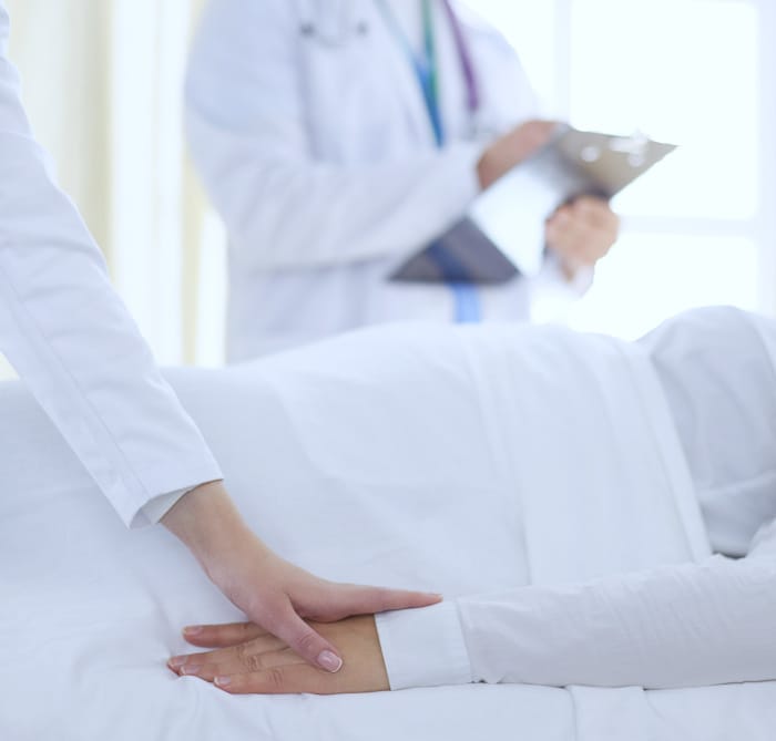 A closeup of a doctor placing there hand on the hand of a female patient in a hospital bed, giving comfort and conveying compassion