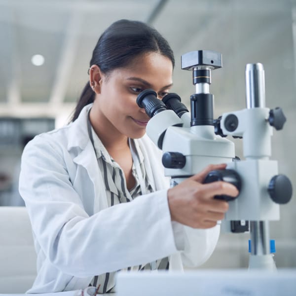 Female researcher confidently looking into microscope