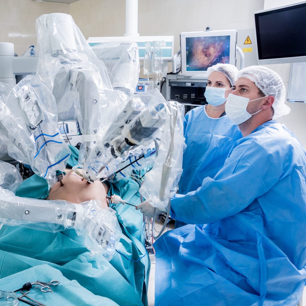 Two physicians sitting in the OR in scrubs performing robotic minimally invasive endometriosis excision surgery