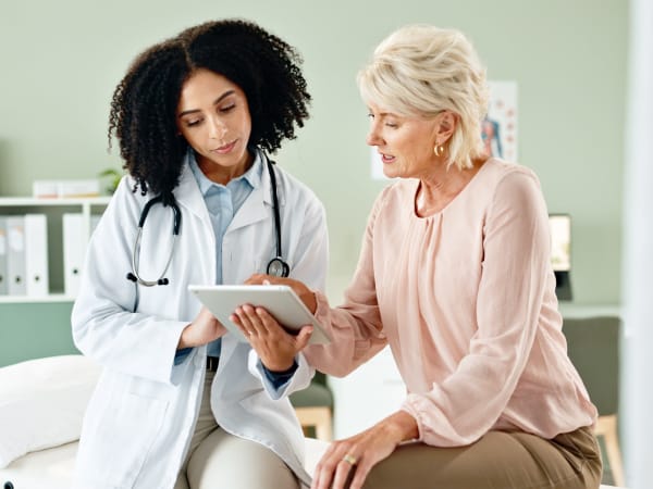 A black female doctor consulting with an older white patient on test results