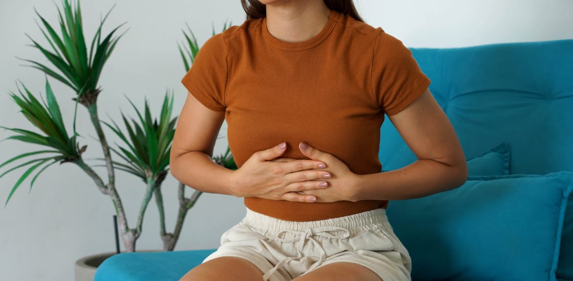 Young woman holds the upper part of the abdomen due to sudden pain.